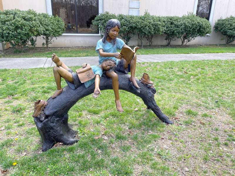Kids reading on log sculpture