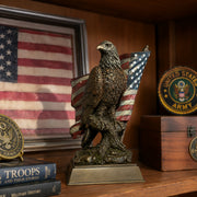 Small American bald eagle with flag statue. Positioned on shelf. American flag. United States Army Patch and books in scene. 