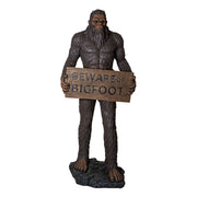 Statue of a Sasquatch holding a 'Beware of Bigfoot' sign on a white background