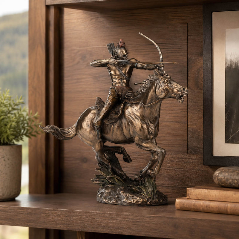 Bronze-finished sculpture of a Native American rider on a galloping horse, displayed on a wooden shelf next to a small potted plant and books.