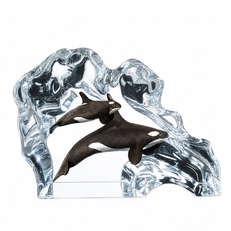 Lucite sculpture of two orca whales swimming through clear water on a white background