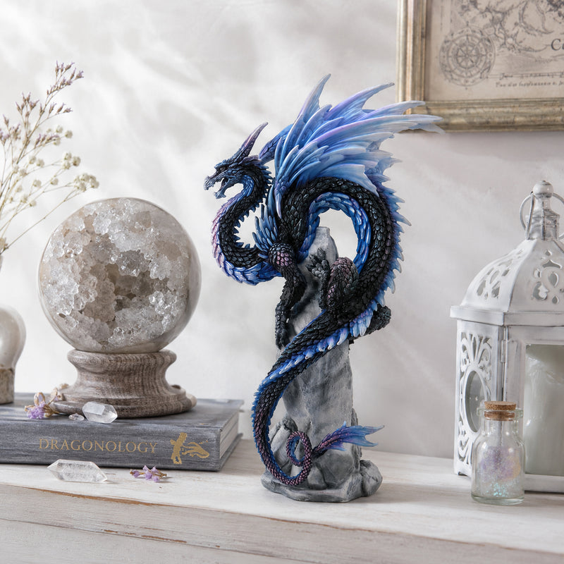 Small decorative dragon statue on a shelf with books and decorative items.