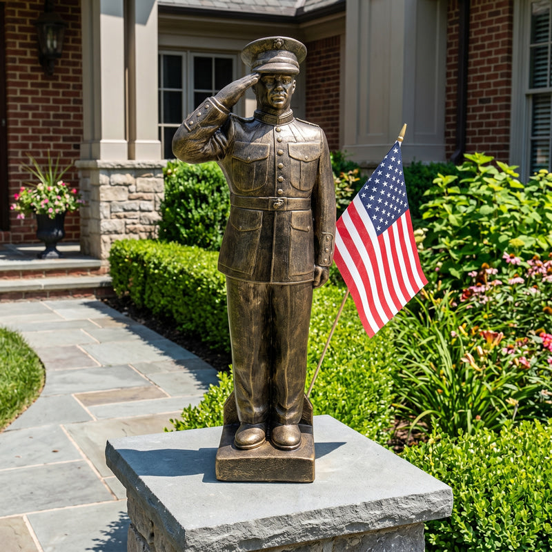 Bronze garden statue of a US Marine saluting with an American flag in front of a house.