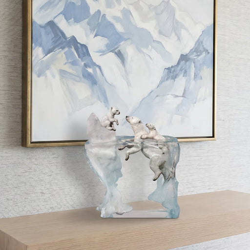 Decorative sculpture of polar bears with cubs on a table in front of abstract art