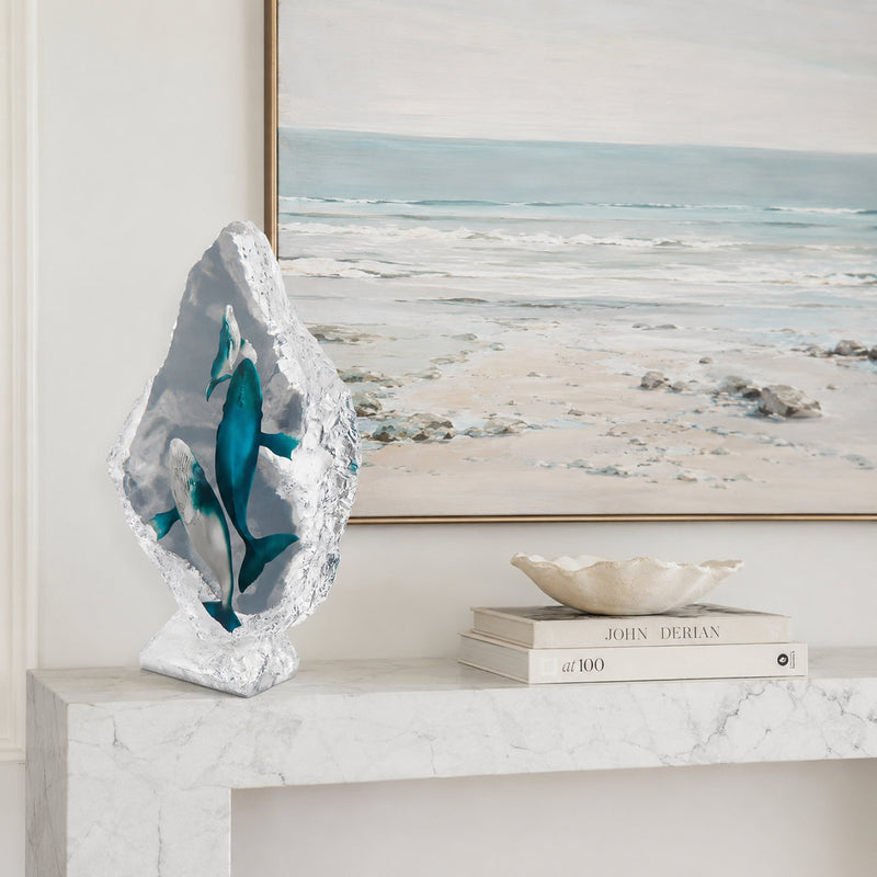 Decorative acrylic whale sculpture on a carrara marble console table with a beach scene painting in the background
