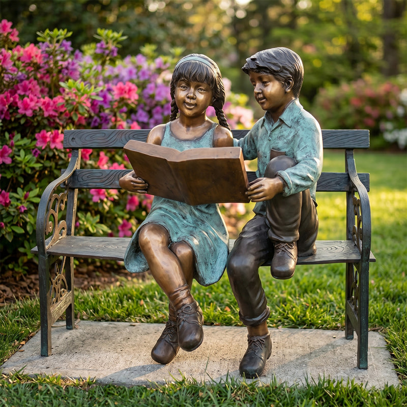 Bronze statue of two children reading on a bench with flowers in the background
