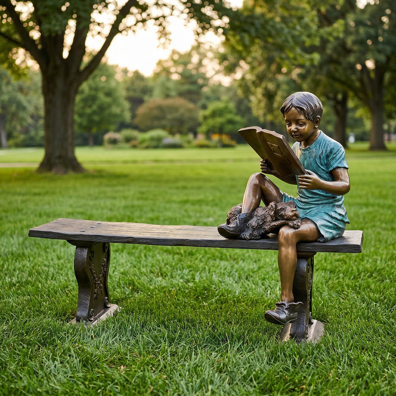 Statue of a child reading a book on a bench in a park setting