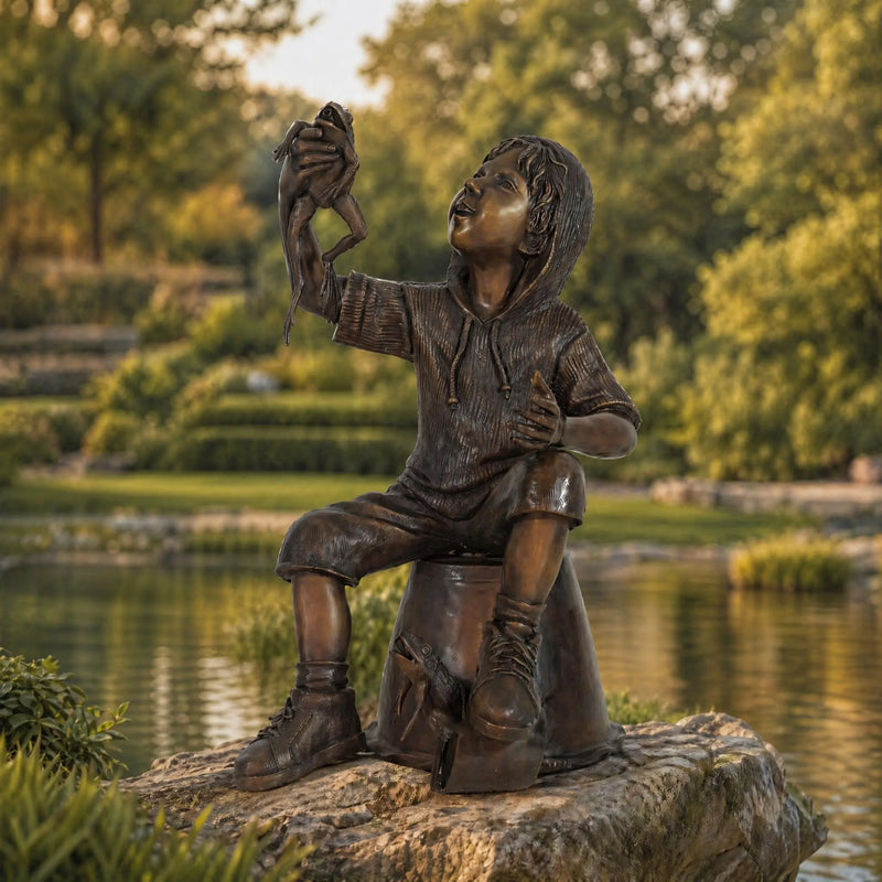 Bronze statue of a child with a frog by a pond