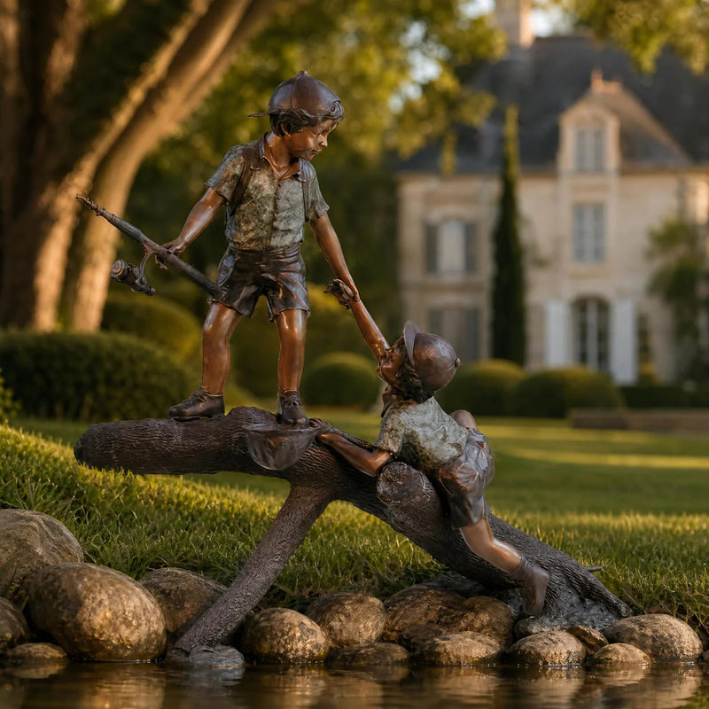 bronze statue of two boys on log with fishing pole and net. Set on edge of pond.