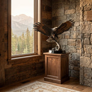 Statue of an eagle on a wooden pedestal in a room with stone walls and a large window showing mountains and trees.