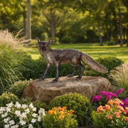Fox statue on a rock surrounded by flowers and greenery