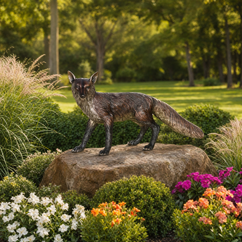 Fox statue on a rock surrounded by flowers and greenery
