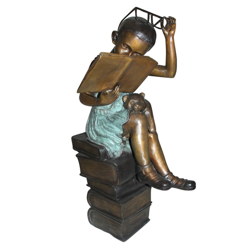 Bronze statue of a child reading a book with a cat on a white background