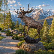 Bronze moose statue on a rock with mountains in the background