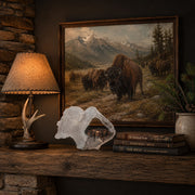 Framed painting of bison in a natural setting on a shelf with a lamp and a decorative buffalo sculpture by artist Kitty Cantrell