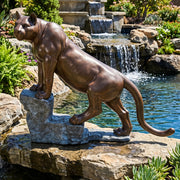 Cougar on rock bronze garden statue near waterfall