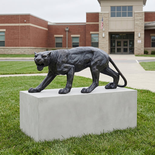 Statue of a cougar on a pedestal in front of a school building