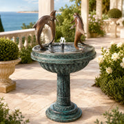 Decorative fountain with dolphin sculptures on a patio with ocean view