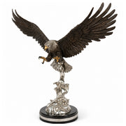 A detailed eagle statue with outstretched wings, perched on a silver-toned wave-like pedestal and round black base, photographed against a plain white background.