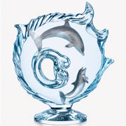 lucite sculpture of dolphins and swirling water design on a white background