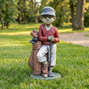 Statue of a boy with golf clubs and a bag on grass