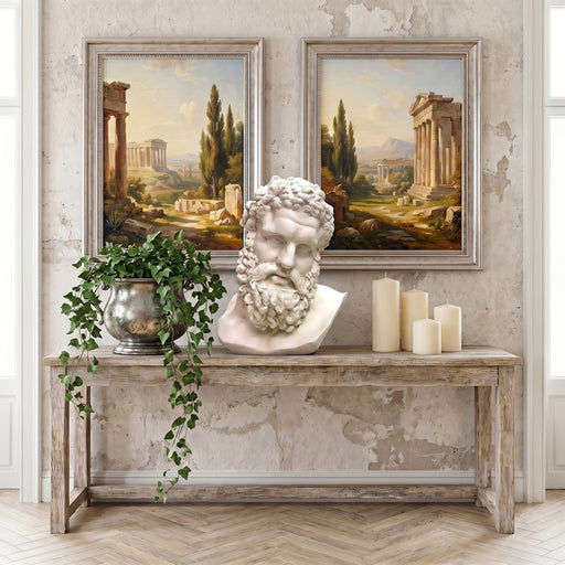 Decorative console table with classical bust of Hercules, candles, and potted plant against a wall with framed landscape paintings.