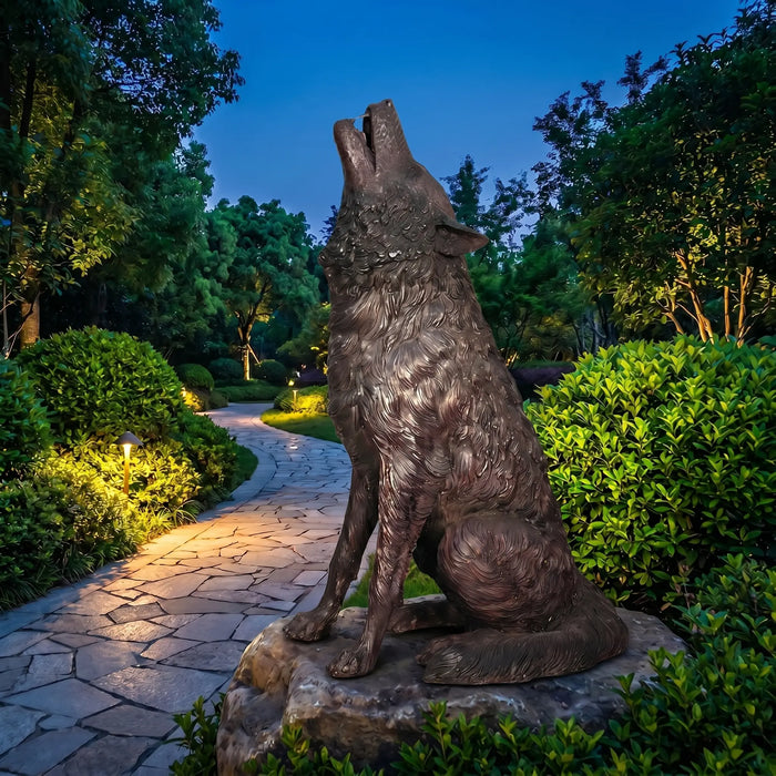 Bronze wolf statue in a garden setting with pathway and trees