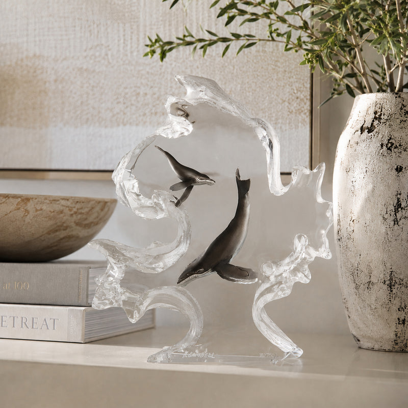 medium lucite table top sculpture of whales on a shelf with books and a vase in the background. Title of sculpture: Mother Nature. Artist Kitty Cantrell