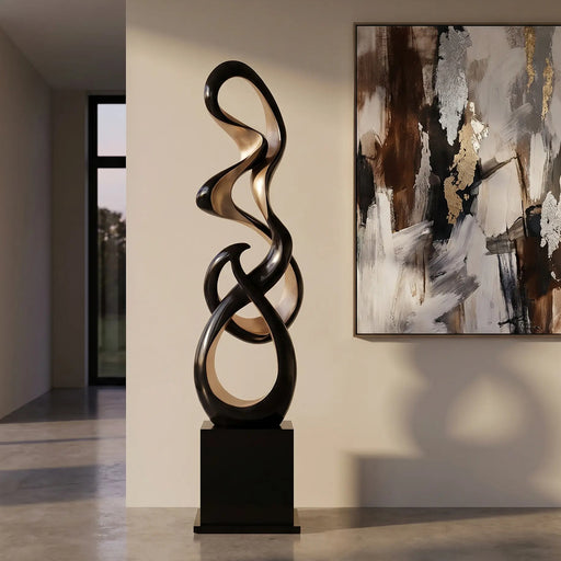 Decorative black and gold floor sculpture in a modern interior setting with abstract art on the wall.