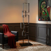 Modern iron floor sculpture with black leather chair next to it. A Picasso style painting hangs on wall.