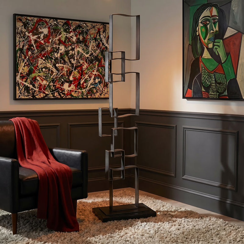 Jackson Pollock style painting hangs on wall. Large iron geometric floor sculpture. 