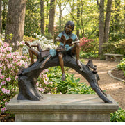 Children reading books on log bronze sculpture in park