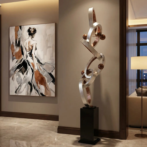Modern interior with abstract sculpture with silver and copper finish and artwork on a wall