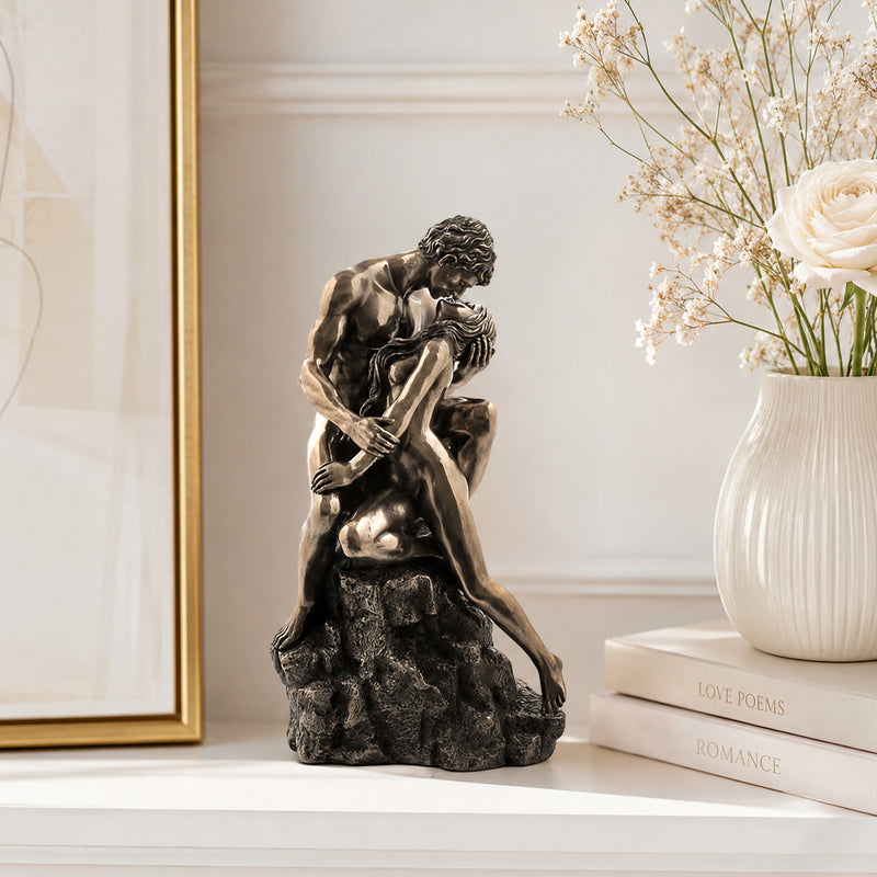 Bronze sculpture of two people embracing on a shelf with decorative items in the background. The Lovers Sculpture