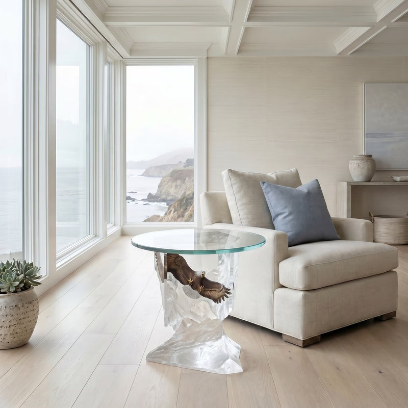 Modern living room with a unique eagle end table and white sofa by large windows with a view of the ocean.