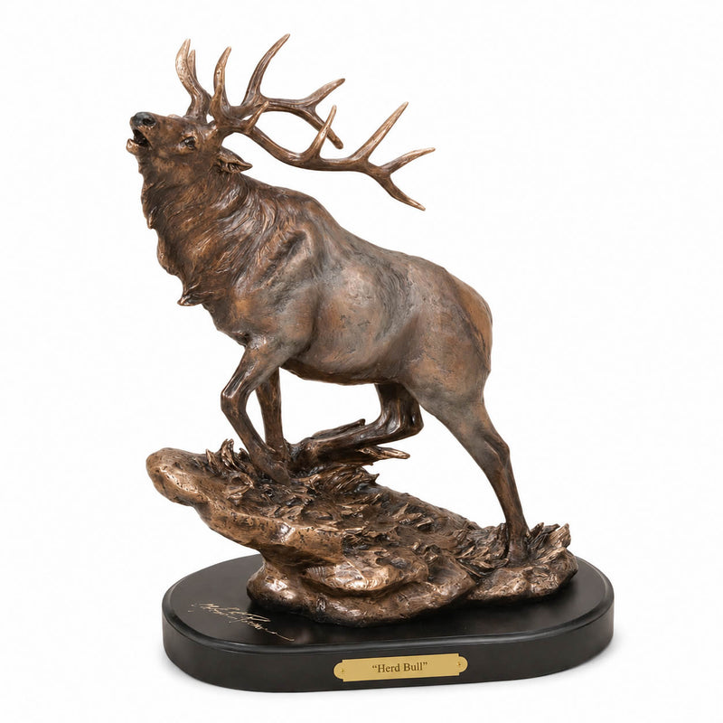 Bull elk sculpture standing on a textured rock base with a black oval pedestal and a gold plaque reading "Herd Bull" on a white background. Marc Pierce Signature Collection