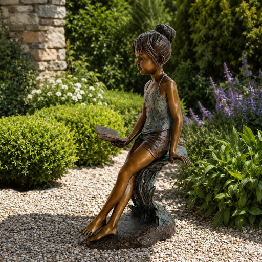 outdoor bronze statue of  young girl reading book in garden