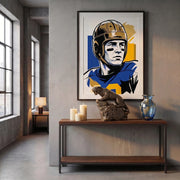 Framed artwork of a football player on a wall above a wooden console table with decorative statue of the Pitt Panthers mascot.