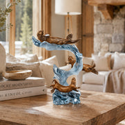 Decorative sculpture of otterson a table in a living room setting. Sculpture title: Playful Motion. Artist: Kitty Cantrell