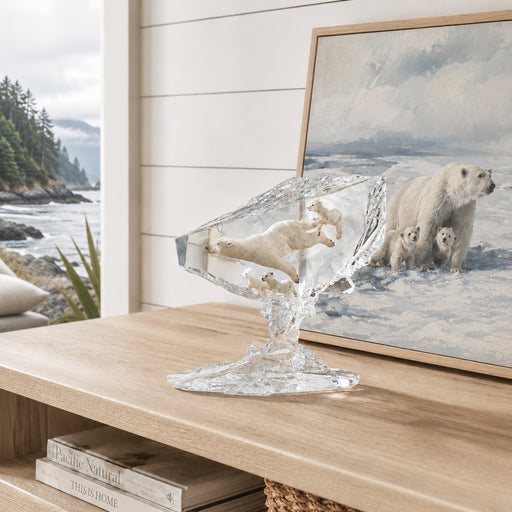 Decorative clear sculpture of polar bears on a wooden surface with a framed picture of polar bears in the background.