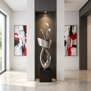 Modern abstract standing silver sculpture in a room with abstract art on the walls