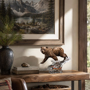 Wooden shelf with a bear figurine, books, and a vase, with a mountain landscape painting in the background.
