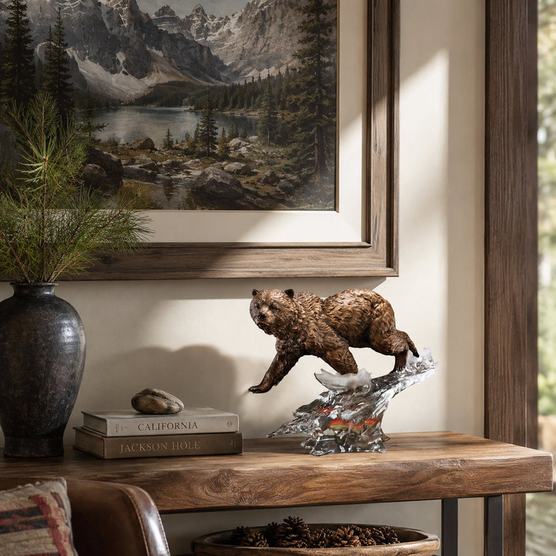 Wooden shelf with a bear figurine, books, and a vase, with a mountain landscape painting in the background.