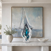 Decorative interior with a large abstract painting of a sailboat, a crystal whale sculpture, and a potted plant on a marble surface.