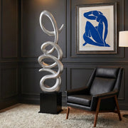 Silver modern standing sculpture in living room. Matisse Blue Nude framed picture hangs  on wall. Black leather chair