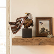 Bronze eagle sculpture with American flag design on a shelf next to a framed photograph of the flag raising at Iowa Jima.