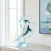 Decorative sculpture of a whale on a dresser a bedroom with a painting on the wall.