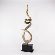 Abstract umber gold sculpture on a black base against a white background