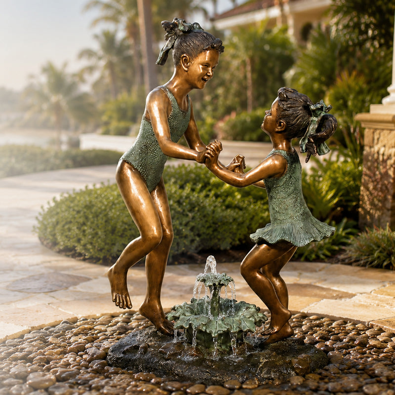 Bronze statue of two children dancing over a small fountain in a garden setting.